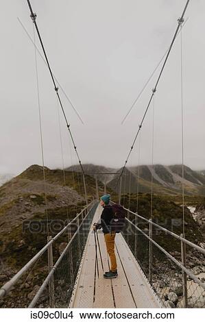 Hiker enjoying view on suspension bridge, Wanaka, Taranaki, New Zealand View Large Photo Image Picture - Hiker enjoying view on suspension bridge, Wanaka, Taranaki, New Zealand. Fotosearch