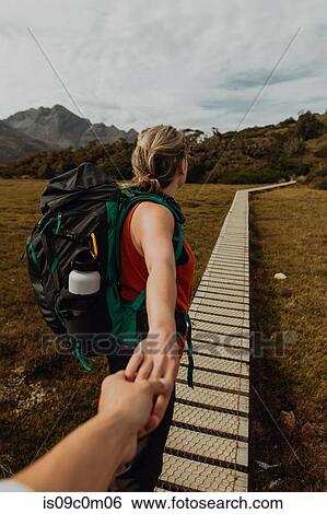 Stock Photograph - Hiker holding friend's hand on trail path, Queenstown, Canterbury, New Zealand. Fotosearch