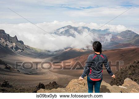 Stock Image - Hiker on edge of mountain top, Haleakala National Park, Maui, Hawaii. Fotosearch