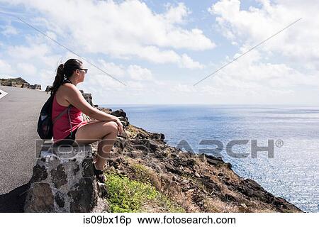 Stock Photography - Hiker on stone wall enjoying view of sea, Makapuu'u, Oahu, Hawaii. Fotosearch