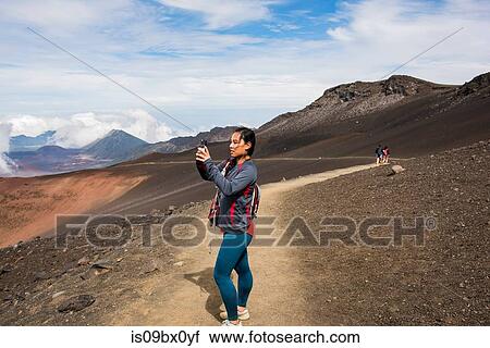 Stock Image - Hiker taking photograph, Haleakala National Park, Maui, Hawaii. Fotosearch
