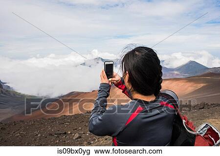 Stock Image - Hiker taking photograph, Haleakala National Park, Maui, Hawaii. Fotosearch