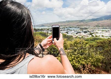 Stock Photography - Hiker taking photograph of town of Halona Beach, Oahu, Hawaii. Fotosearch