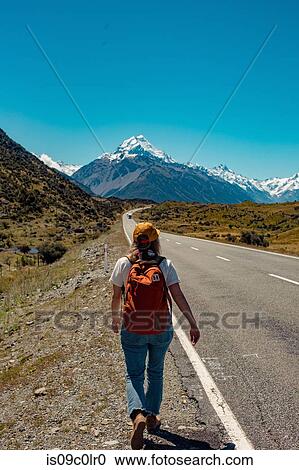 Stock Image - Hiker walking towards mountains, Wanaka, Taranaki, New Zealand. Fotosearch