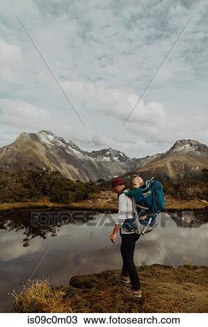 Stock Image - Hiker with baby by lake, Queenstown, Canterbury, New Zealand. Fotosearch