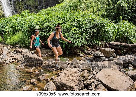 Stock Photography - Hikers crossing stream, Waipipi Trail, Maui, Hawaii. Fotosearch