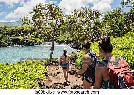 Stock Image - Hikers on hiking trail, Waianapanapa State Park, Maui, Hawaii. Fotosearch