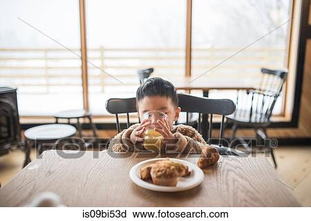Stock Image - Little boy drinking juice in restaurant. Fotosearch