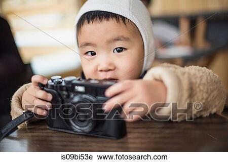 Little boy holding camera on table View Large Photo Image Stock Image - Little boy holding camera on table. Fotosearch