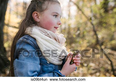 Picture - Little girl holding frog in forest. Fotosearch