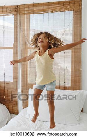Little girl jumping with arms open on bed in beach house View Large Photo Image Stock Image - Little girl jumping with arms open on bed in beach house. Fotosearch