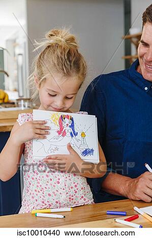Stock Image - Little girl showing off drawing at home. Fotosearch