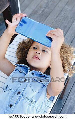 Stock Image - Little girl using smartphone on bench. Fotosearch