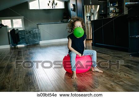 Little girl with balloon in mouth bouncing on gym ball at home View Large Photo Image Stock Image - Little girl with balloon in mouth bouncing on gym ball at home. Fotosearch
