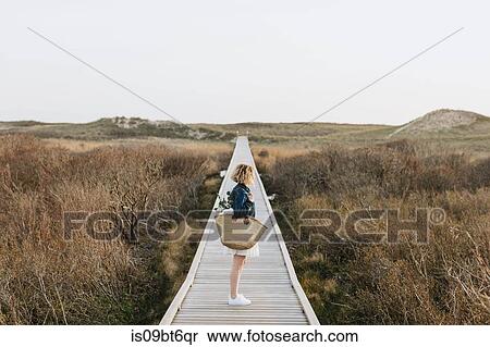 Lone young woman looking out from coastal dune boardwalk, Menemsha, Martha's Vineyard, Massachusetts, USA View Large Photo Image Stock Photography - Lone young woman looking out from coastal dune boardwalk, Menemsha, Martha's Vineyard, Massachusetts, USA. Fotosearch