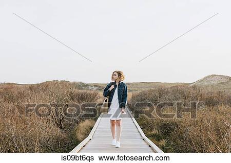 Lone young woman strolling on coastal dune boardwalk, Menemsha, Martha's Vineyard, Massachusetts, USA View Large Photo Image Stock Photograph - Lone young woman strolling on coastal dune boardwalk, Menemsha, Martha's Vineyard, Massachusetts, USA. Fotosearch
