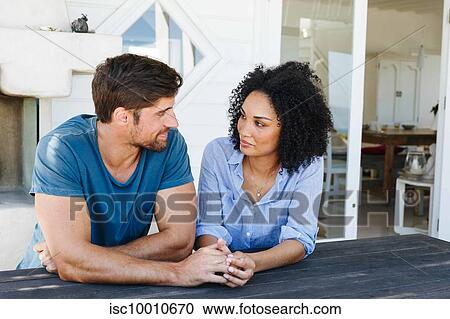 Stock Image - Loving couple staring at each other in beach house. Fotosearch