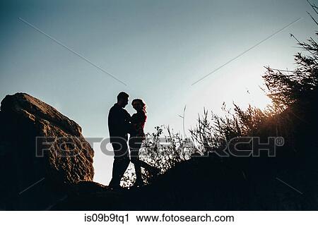 Stock Image - Low angle view of romantic mid adult couple backlit on coast, Odessa Oblast, Ukraine. Fotosearch