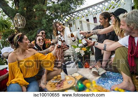 Male and female friends making a toast with bottled beer at community garden party View Large Photo Image Stock Photography - Male and female friends making a toast with bottled beer at community garden party. Fotosearch