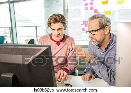 Male digital designer explaining design to trainee at office desk View Large Photo Image Stock Photography - Male digital designer explaining design to trainee at office desk. Fotosearch
