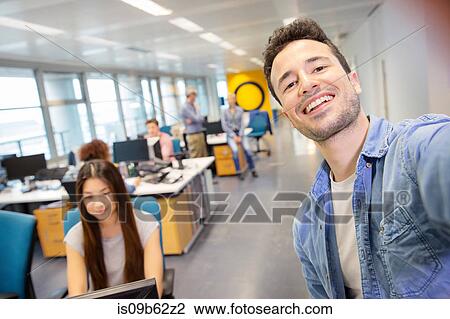 Stock Image - Male digital designer taking selfie in office. Fotosearch
