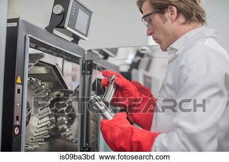 Stock Image - Male worker in thread factory, taking beakers from chemical oven. Fotosearch