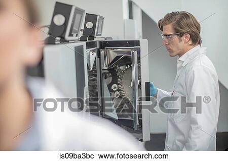 Stock Image - Male worker in thread factory, using chemical oven. Fotosearch