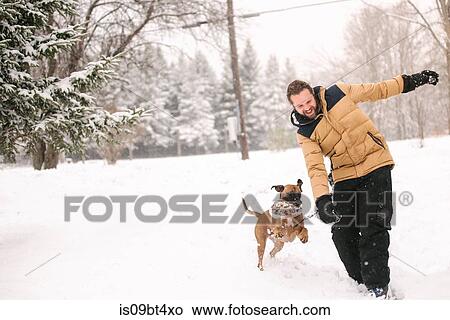 Picture - Man and pet dog playing with toy. Fotosearch
