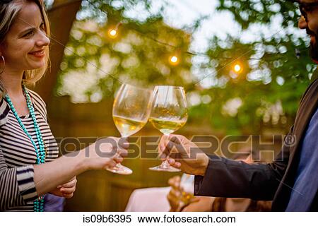 Stock Photography - Man and woman at garden party, holding wine glasses, making a toast. Fotosearch