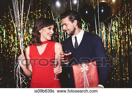 Stock Photograph - Man and woman at party, holding drinks, smiling. Fotosearch