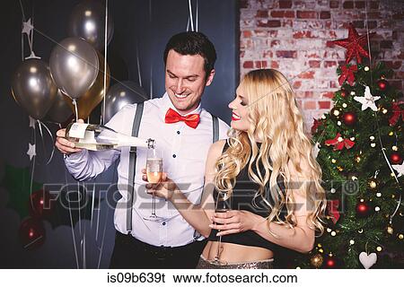 Stock Photograph - Man and woman at party, man pouring champagne into woman's glass. Fotosearch