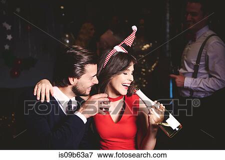 Stock Photo - Man and woman sitting together at party, woman drinking from champagne bottle. Fotosearch