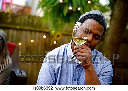 Man at garden party, holding wine glass, inspecting wine View Large Photo Image Stock Image - Man at garden party, holding wine glass, inspecting wine. Fotosearch
