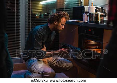 Man checking on food in oven View Large Photo Image Stock Photograph - Man checking on food in oven. Fotosearch