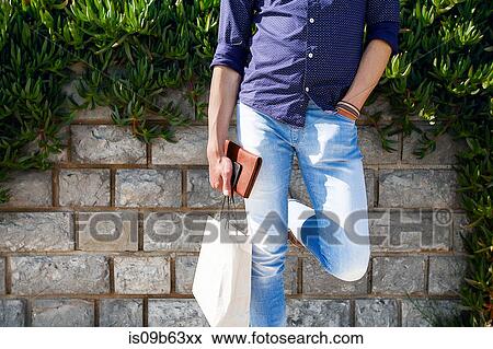 Man holding shopping bags by brick wall View Large Photo Image Stock Photo - Man holding shopping bags by brick wall. Fotosearch