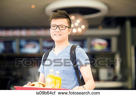 Man holding tray of fast food looking at camera smiling View Large Photo Image Stock Image - Man holding tray of fast food looking at camera smiling. Fotosearch