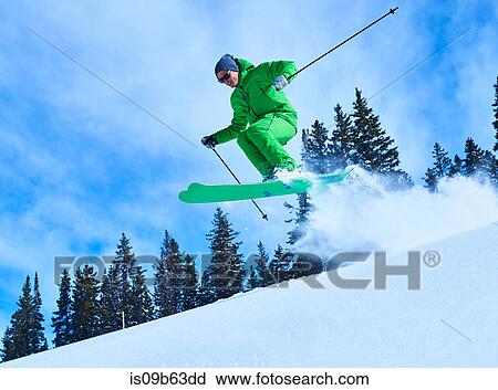 Stock Image - Man jumping while skiing down snow covered mountainside, Aspen, Colorado, USA. Fotosearch