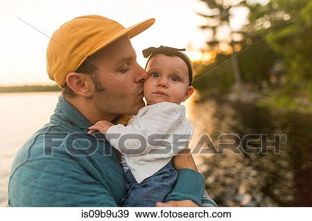 Man kissing baby daughter at lakeside View Large Photo Image Stock Photo - Man kissing baby daughter at lakeside. Fotosearch