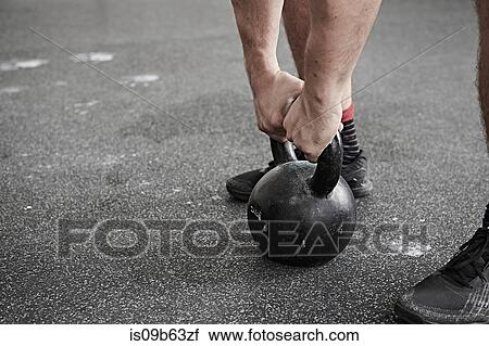 Stock Image - Man lifting kettlebell in cross training gym. Fotosearch