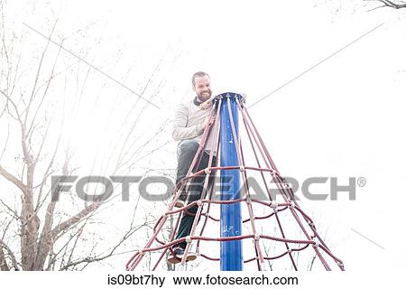 Man on top of spider web tower in park View Large Photo Image Stock Photo - Man on top of spider web tower in park. Fotosearch