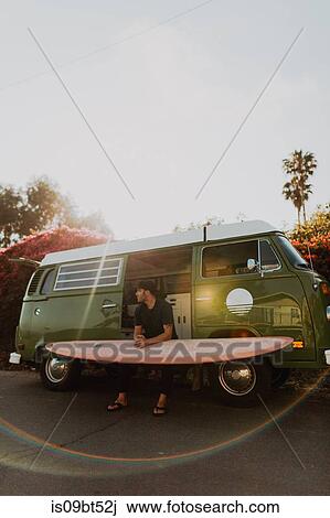 Stock Image - Man on van road trip with his surfboard, Ventura, California, US. Fotosearch