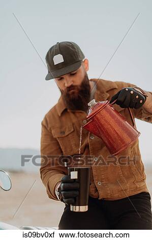 Stock Image - Man pouring hot water into mug, Trona Pinnacles, California, US. Fotosearch