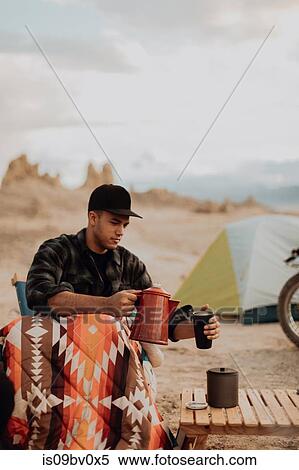 Stock Photography - Man pouring hot water into mug, Trona Pinnacles, California, US. Fotosearch