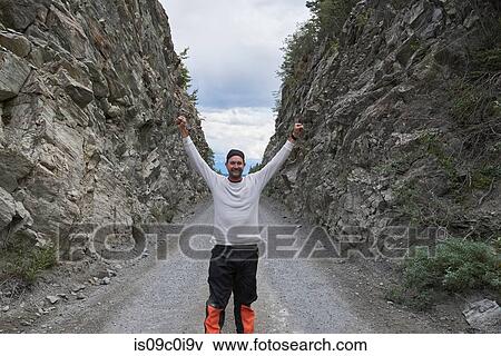 Man raising hands between rocky hills, Chitina, Alaska, United States View Large Photo Image Stock Photo - Man raising hands between rocky hills, Chitina, Alaska, United States. Fotosearch