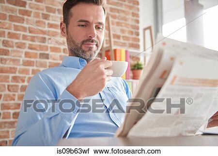 Stock Image - Man reading newspaper drinking coffee. Fotosearch