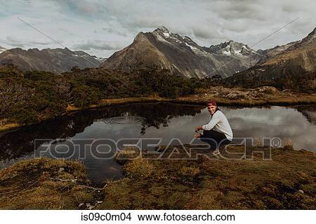 Picture - Man relaxing by lake, Queenstown, Canterbury, New Zealand. Fotosearch