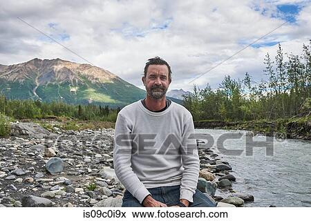 Man relaxing by stream, scenic view in background, Chitina, Alaska, United States View Large Photo Image Stock Photo - Man relaxing by stream, scenic view in background, Chitina, Alaska, United States. Fotosearch