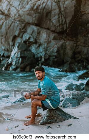 Stock Image - Man relaxing on beach, Big Sur, California, United States. Fotosearch