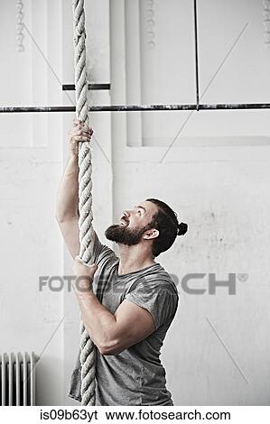 Man rope climbing in cross training gym View Large Photo Image Stock Photograph - Man rope climbing in cross training gym. Fotosearch
