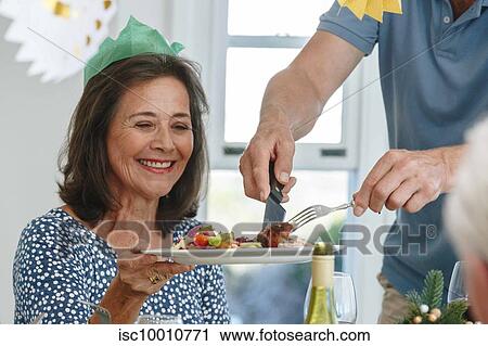 Man serving woman at dining table in home party View Large Photo Image Stock Image - Man serving woman at dining table in home party. Fotosearch